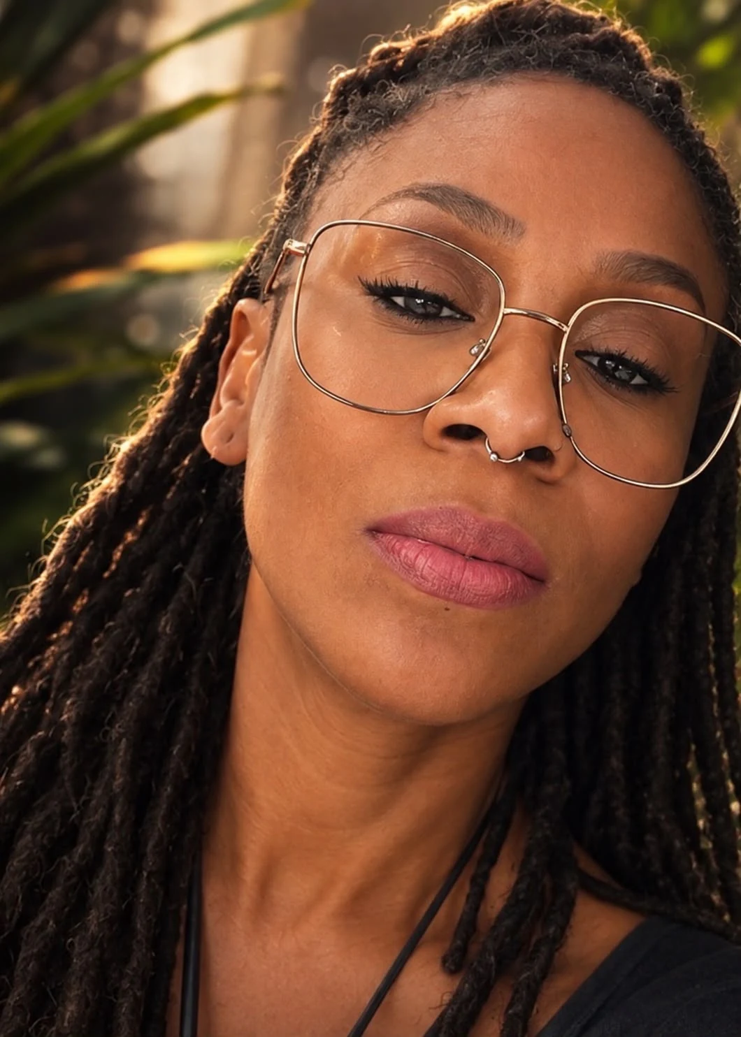 Close-up portrait of Jahina Noël wearing glasses, with braided hair.